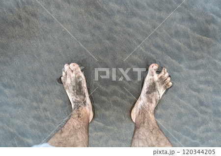 Bare foot on black sand, black volcanic beach barefoot person, dirty family feet on dark sea sand 120344205