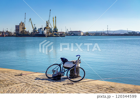 Bicycle and fishing rods lying by the tranquil waterfront at the harbor 120344599