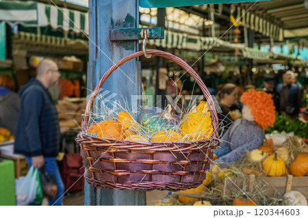 Wicker basket with colorful pumpkins, autumn harvest at lively market 120344603
