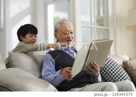 elderly asian grandfather having a good time with grandson at home 120345375