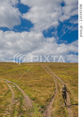 Young Woman Tourist Walking Up Mountain Hill 120345396