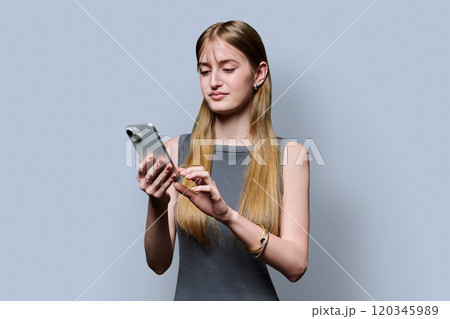 Young beautiful woman using smartphone on grey studio background Young beautiful woman using smartphone on grey studio background 120345989