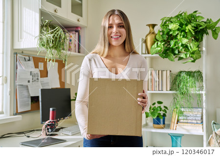 Young woman at home unpacks cardboard box with online purchases Young woman at home unpacks cardboard box with online purchases 120346017