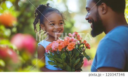 Joyful daughter presenting flowers to her father in a scenic garden setting 120347346