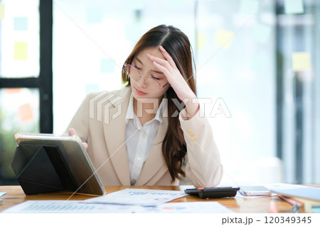Businesswoman feeling stressed while analyzing data at her desk Businesswoman feeling stressed while analyzing data at her desk 120349345