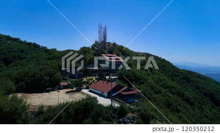 Mountain refuge nestled in lush green forest under blue sky 120350212