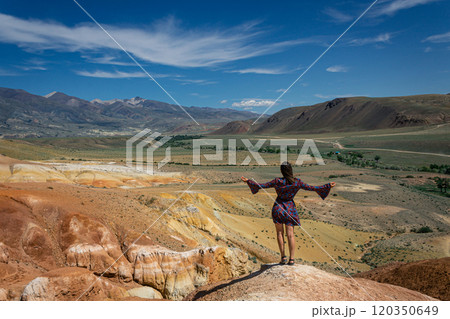 Travel concept: woman in a short dress, hands showing how big and beautiful tourist attraction Altai Mars Travel concept: woman in a short dress, hands showing how big and beautiful tourist attraction Altai Mars 120350649
