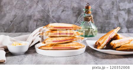 Grilled triangle sandwiches with cheese and sausage on a plate on a table web banner Grilled triangle sandwiches with cheese and sausage on a plate on a table web banner 120352008