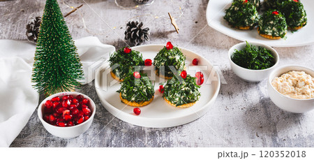 Tuna, egg and dill salad shaped like Christmas trees on crackers on a plate web banner 120352018