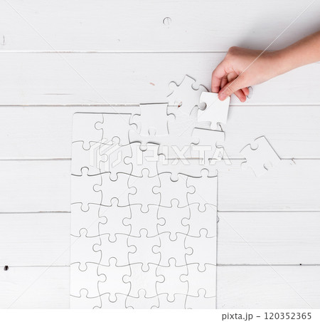 hand holding a piece of white uncompleted puzzle hand holding a piece of white uncompleted puzzle 120352365