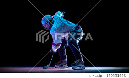 Man, professional hockey player dressed in white, standing into powerful skating stance on ice against black studio background in neon light Man, professional hockey player dressed in white, standing into powerful skating stance on ice against black studio background in neon light 120353468