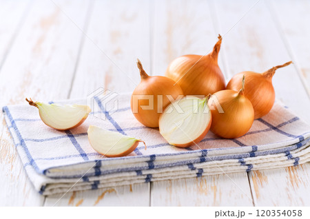 half an onion and a whole yellow onions on a light kitchen table, selective focus. 120354058