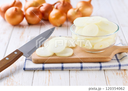 chopped yellow onions in a glass bowl on a white wooden table, selective focus. 120354062