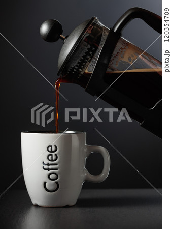 Pouring French press coffee into a cup. Pouring French press coffee into a cup. 120354709