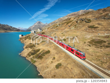 Aerial view of red train near azure mountain lake in autumn Aerial view of red train near azure mountain lake in autumn 120354943