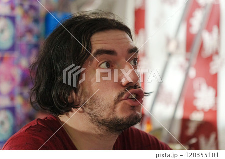 Man displays a look of astonishment, reflecting the excitement of an ongoing local festival filled with bright colors and energy. Man displays a look of astonishment, reflecting the excitement of an ongoing local festival filled with bright colors and energy. 120355101