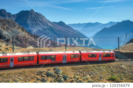 Red modern train is winding through the swiss alps on a sunny day 120356879