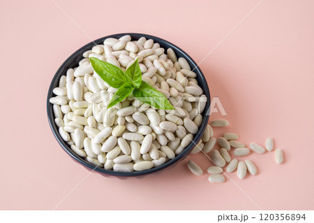 Bowl full of white beans over pastel pink background. 120356894