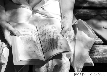 ベンチで本を読む女性の手 120357799