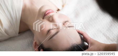 仰向けでヘッドマッサージやヘッドスパなどをするイメージのバナーのクローズアップ　俯瞰 120359545