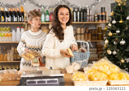 Adolescence boy with mother choose consider snacks in shop on eve of New Year 120363121