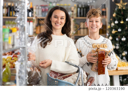 Adolescence boy with mother choose consider snacks in shop on eve of New Year 120363190