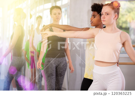Teenage girl training in pair with dark-skinned boy in ballet studio Teenage girl training in pair with dark-skinned boy in ballet studio 120363225