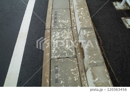 アスファルト道路の濡れた路肩の側溝 120363456