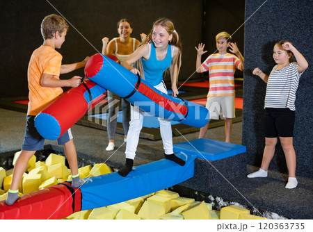 Children having funny wrestling by inflatable logs in indoor amusement park 120363735
