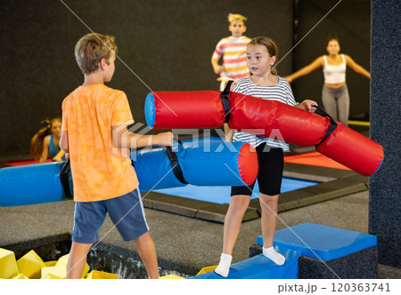 Team of friends playing with inflatable sticks in amusement park 120363741