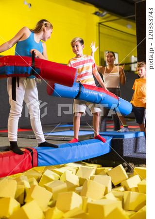 Happy child school boy and teenage girl friends fighting by inflatable logs while spending weekend together in entertainment center Happy child school boy and teenage girl friends fighting by inflatable logs while spending weekend together in entertainment center 120363743