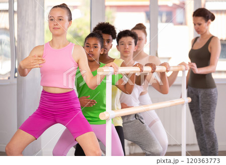 Woman teacher corrects teenagers in plie movement 120363773