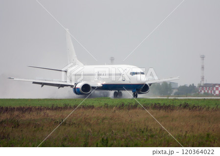 Passenger airplane heading on the runway with extended spoilers in heavy rain Passenger airplane heading on the runway with extended spoilers in heavy rain 120364022