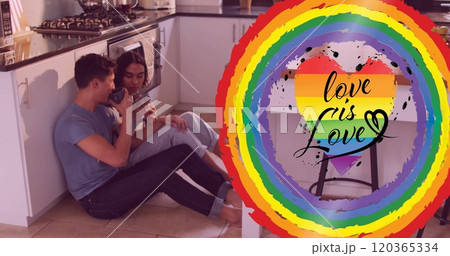 Image of love is love text and rainbow heart over diverse gay male couple talking in kitchen 120365334