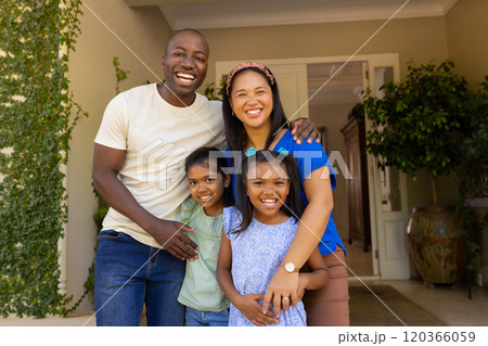 Smiling family of four with daughters standing together outside home, enjoying quality time 120366059