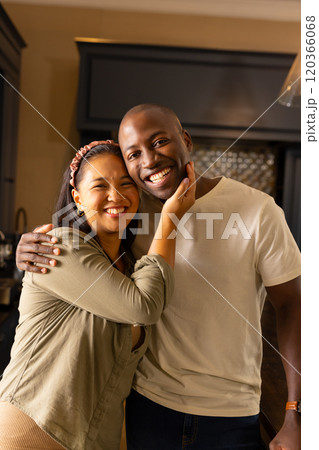 Smiling multiracial couple embracing in kitchen, enjoying quality time together at home 120366068