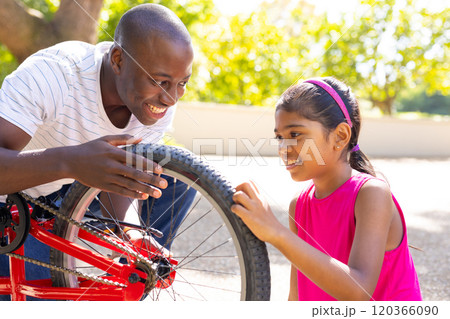 Fixing bicycle tire, father and daughter bonding outdoors in sunny park Fixing bicycle tire, father and daughter bonding outdoors in sunny park 120366090