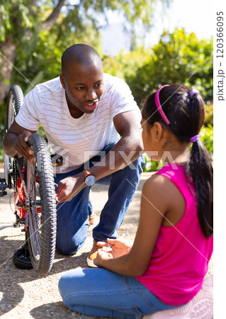 Fixing bicycle, father teaching daughter how to repair bike outdoors Fixing bicycle, father teaching daughter how to repair bike outdoors 120366095