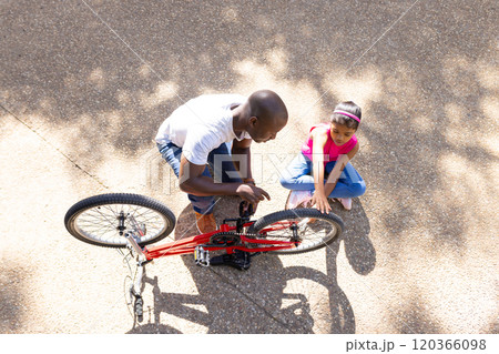 Fixing bicycle, father teaching daughter how to repair bike outdoors Fixing bicycle, father teaching daughter how to repair bike outdoors 120366098