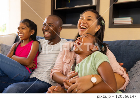 Laughing together, happy family of four sitting on couch at home Laughing together, happy family of four sitting on couch at home 120366147