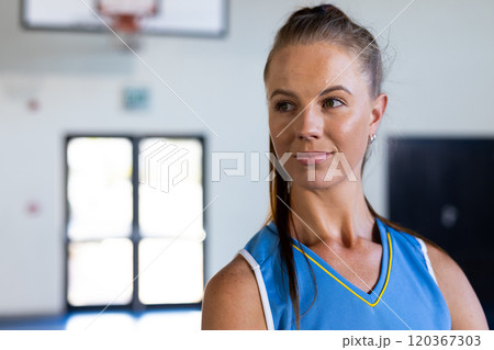 Female basketball player in blue jersey standing confidently in gymnasium, copy space Female basketball player in blue jersey standing confidently in gymnasium, copy space 120367303