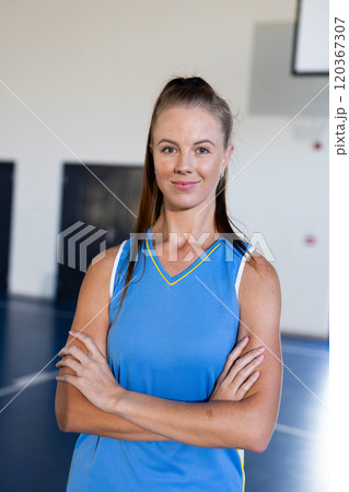 In gym, female basketball player in blue jersey standing with arms crossed In gym, female basketball player in blue jersey standing with arms crossed 120367307