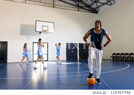 Male african american basketball coach with female players practicing, copy space 120367346