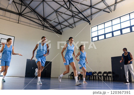 Playing basketball, female team practicing on court with coach in school gym 120367391