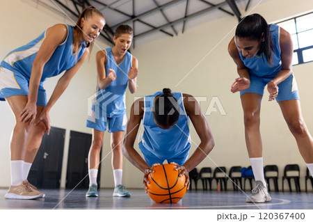 Basketball team encouraging teammate holding ball during practice in gym 120367400