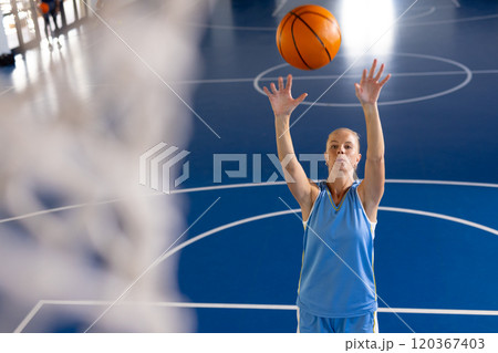 Playing basketball, woman shooting ball towards hoop on indoor court, copy space Playing basketball, woman shooting ball towards hoop on indoor court, copy space 120367403