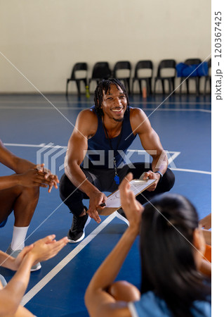 Coaching basketball team, man holding clipboard and smiling at players Coaching basketball team, man holding clipboard and smiling at players 120367425