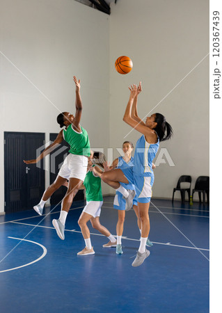 Playing basketball, female athletes competing in indoor court game, jumping for ball Playing basketball, female athletes competing in indoor court game, jumping for ball 120367439