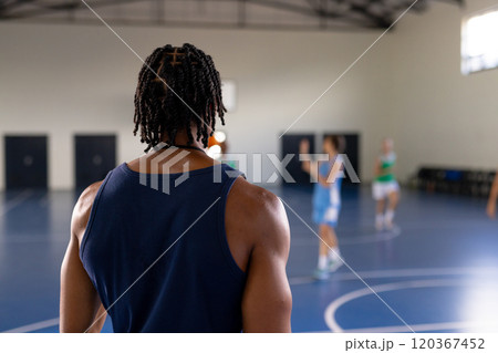 Watching female basketball players practicing on indoor court, male coach observing game Watching female basketball players practicing on indoor court, male coach observing game 120367452