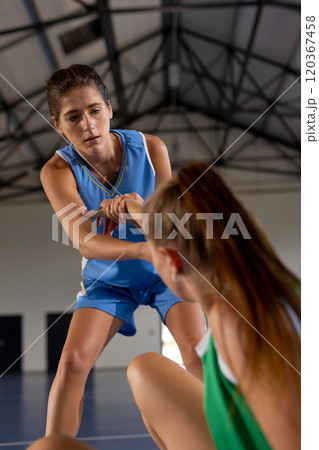 Helping teammate up, female basketball players in sports uniforms on court 120367458